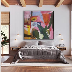 May include: A bedroom with a large abstract painting above the bed. The painting features a pink, green, yellow, and red color scheme. The bed has a gray comforter and is made up with white pillows. The room has wooden floors and a wooden ceiling.