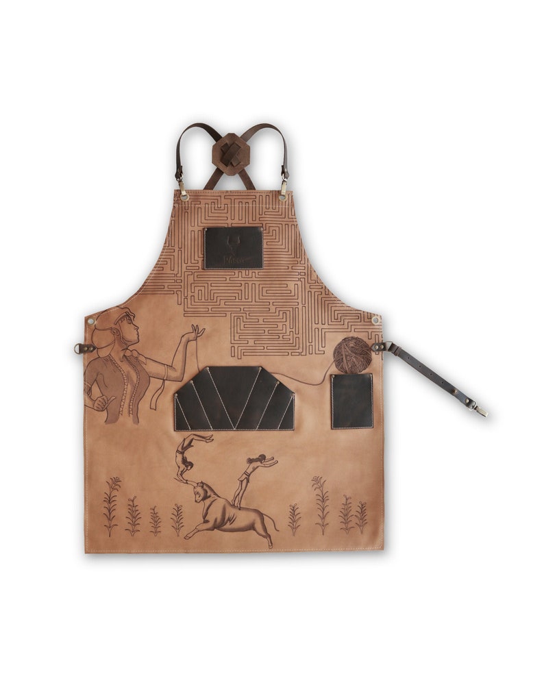 May include: A brown leather apron with a maze pattern, a woman figure, and a bull with two figures on its back. The apron has two pockets and adjustable straps. The text "The Maker" is printed on the apron.