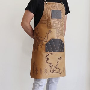 May include: A brown leather apron with a maze pattern and a pocket. The apron has a design of a woman holding a bull's horn and a man jumping over the bull. The apron has a leather patch with the word "Tasco" on it.