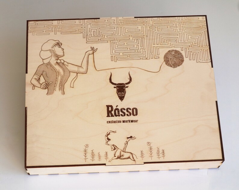 May include: A wooden box with a laser-engraved design. The design features a woman holding a ball of yarn, a bull, and the text "R&aacute;sso exclusive workwear".