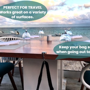 a table set for dining with a view of the ocean, featuring a sign that reads "Perfect for travel. Works great on a variety of surfaces. Keep your bag safe when going out to eat."