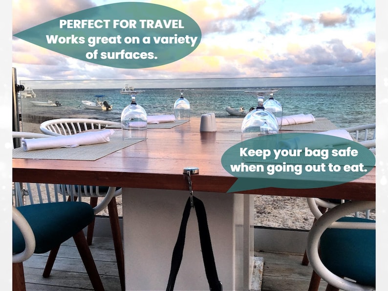 a table set for dining with a view of the ocean, featuring a sign that reads "Perfect for travel. Works great on a variety of surfaces. Keep your bag safe when going out to eat."