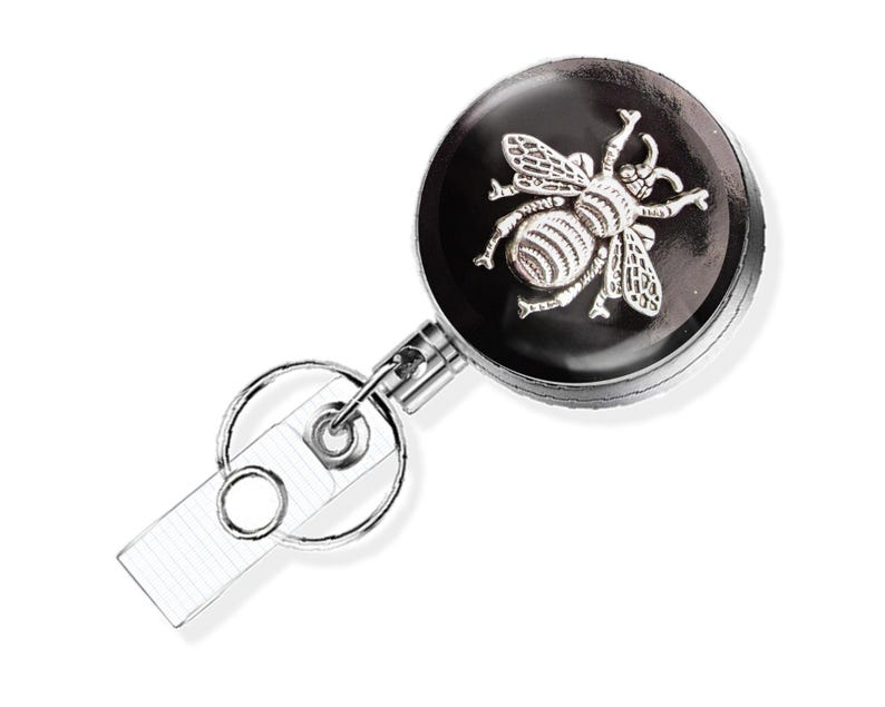 A silver-colored metal badge or lanyard with a bee design on it.