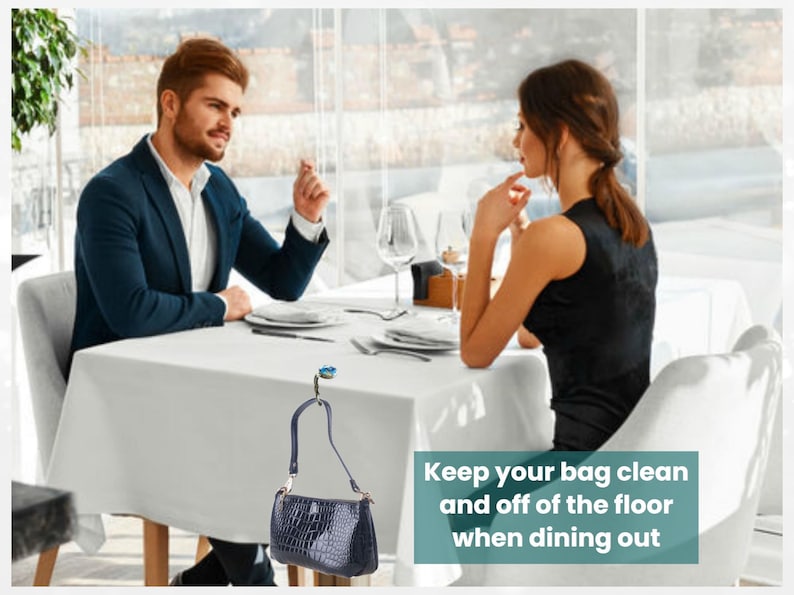 A man and a woman are seated at a table in a restaurant, engaged in conversation. The man is wearing a blue jacket, and the woman is wearing a black dress. The table is set with plates, silverware, and glasses, suggesting a formal dining setting. A handbag is hanging on the wall, and there is text in the image that reads "Keep your bag clean and off of the floor when dining out".