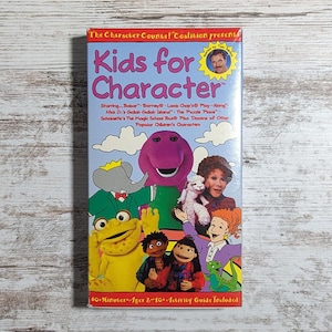 May include: A vintage VHS tape titled "Kids for Character" featuring cartoon characters like Barney, Babar, and Lamb Chop. The cover is colorful with illustrations and text, including "60+ Minutes" and "Ages 2-10."
