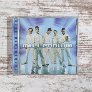 May include: A CD case featuring the Backstreet Boys' album "Millennium." The cover art shows the five band members in white outfits against a blue and silver background. The album title is prominently displayed in silver lettering.