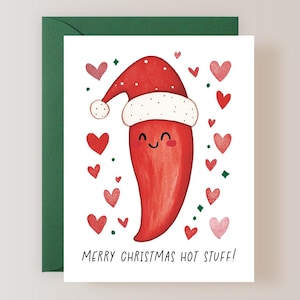 May include: A Christmas card featuring a red chili pepper wearing a Santa hat, surrounded by red hearts and green diamond shapes. The text "MERRY CHRISTMAS HOT STUFF!" is printed at the bottom of the card. The card is inside a green envelope.