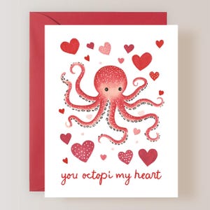 May include: A Valentine's Day card featuring a red octopus with a pink heart on its head surrounded by red and pink hearts. The card reads "you octopi my heart".