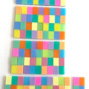 May include: A collection of colorful, rectangular tiles arranged in rows. The tiles are in shades of pink, orange, yellow, green, blue, and purple. The arrangement is on a white background.