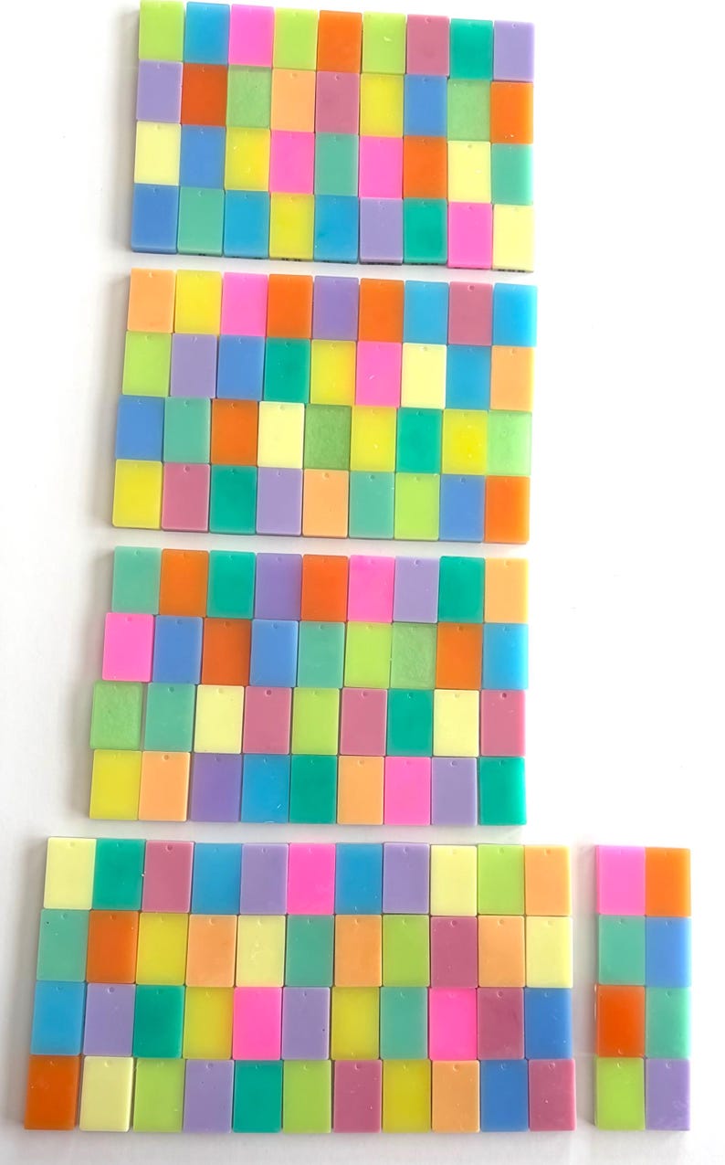 May include: A collection of colorful, rectangular tiles arranged in rows. The tiles are in shades of pink, orange, yellow, green, blue, and purple. The arrangement is on a white background.