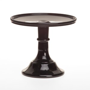 May include: A black, glossy cake stand with a round top and a pedestal base. The stand is made of a solid material and has a smooth, reflective surface. The design is simple and elegant, suitable for displaying desserts or decorative items.