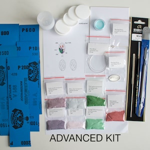 May include: Advanced enamel kit with various colored enamel powders, tools, and silver findings. The kit includes a small instruction sheet with a diagram of a flower design.