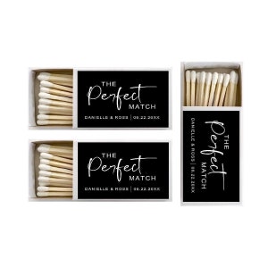May include: Two black matchboxes with white text that reads "The Perfect Match" with the date and names "Danielle & Ross" printed below. The matchboxes are filled with wooden matches.