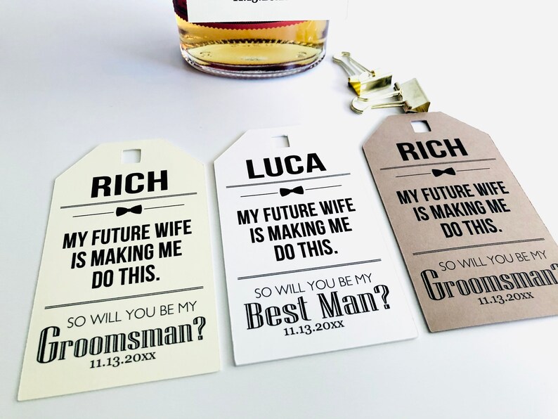 May include: Three gift tags with brown and white paper stock. The tags have black text that reads "My future wife is making me do this." and "So will you be my ...?" with the options "Groomsman?" or "Best Man?" and the date "11.13.20XX".