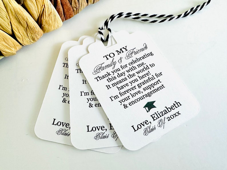 May include: White graduation favor tags with black text. The text reads "To My Family & Friends Thank you for celebrating this day with me. It means the world to have you here! I'm forever grateful for your love, support & encouragement Love, Elizabeth Class of 20xx"