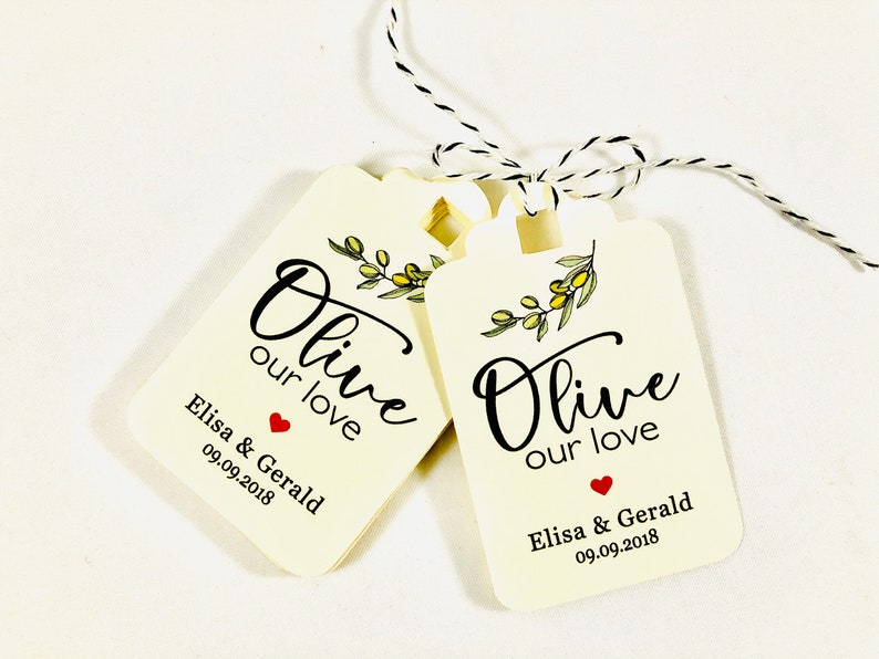 May include: Two cream-colored wedding favor tags with black text that reads "Olive our love" and a small red heart. The tags also include the names "Elisa & Gerald" and the date "09.09.2018".