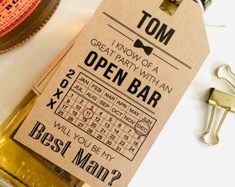 Może przedstawiać: Brązowa papierowa etykieta z tekstem "Tom I know of a great party with an open bar" i kalendarzem, na którym zaznaczono miesiąc grudzień. Etykieta zawiera również napis "Will you be my Best Man?"