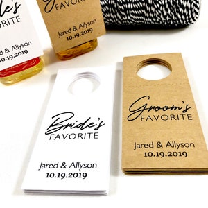 May include: Two sets of wedding favor bottle tags. One set is white with black text and the other is brown with black text. Both sets say "Bride's Favorite" and "Groom's Favorite" with the couple's names and wedding date.