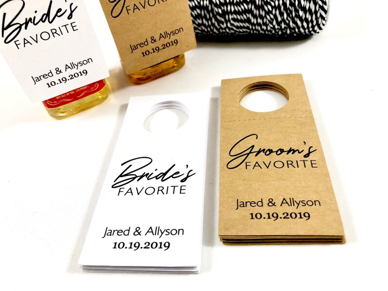 May include: Two sets of wedding favor bottle tags. One set is white with black text and the other is brown with black text. Both sets say "Bride's Favorite" and "Groom's Favorite" with the couple's names and wedding date.