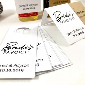May include: White wedding favor tags with the text "Bride's Favorite" and "Groom's Favorite" with the names Jared & Allyson and the date 10.19.2019.