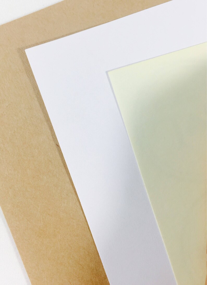 May include: Three sheets of paper stacked on top of each other. The bottom sheet is brown, the middle sheet is white, and the top sheet is a light yellow.