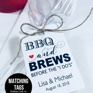 May include: White tag with black text that reads "BBQ and BREWS BEFORE THE "I DO'S" Lisa & Michael August 18, 2018". The tag is tied to a clear plastic fork and spoon.