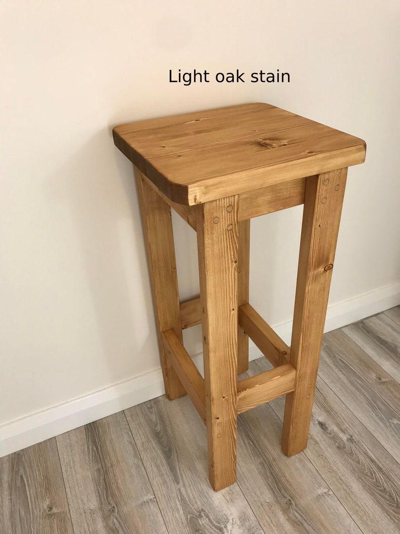 K&ouml;nnte beinhalten: Ein hell eichenfarbener Holzstuhl mit quadratischer Sitzfl&auml;che und vier stabilen Beinen. Der Text "Light oak stain" ist auf dem Bild zu sehen. Der Hocker ist aus Holz und hat eine nat&uuml;rliche Oberfl&auml;che.