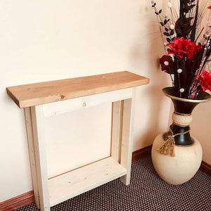 May include: A small wooden console table with a natural wood top and a white painted frame. The table has a lower shelf. The table is approximately 91 cm long, suitable for a hallway or living room.