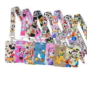 May include: A collection of seven vertical ID badge holders with matching lanyards, each featuring colorful cartoon character prints including Mickey Mouse, Minnie Mouse, Donald Duck, Daisy Duck, Pluto, and Goofy with various patterns and film strip designs.