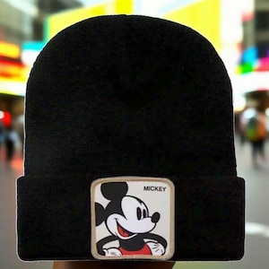 May include: Black beanie hat with a rectangular patch featuring a smiling Mickey Mouse cartoon character. The patch has a beige border and the word "MICKEY" in white text.