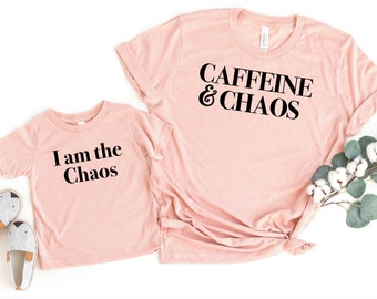 May include: Two pink t-shirts with black text. The larger shirt says "Caffeine & Chaos". The smaller shirt says "I am the Chaos".