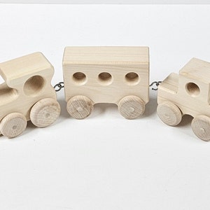 May include: A wooden toy train set with an engine, a boxcar, and a caboose. The train is made of natural wood and has a simple design.