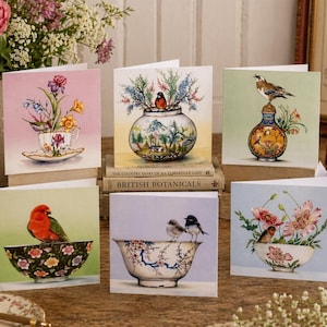 May include: Six greeting cards with watercolour illustrations of birds and flowers in decorative bowls and vases. The cards have a vintage aesthetic, with soft pastel backgrounds and detailed artwork. Each card is unique.