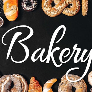 May include: An assortment of baked goods, such as bread, pastries, and doughnuts, surrounds the white script word "Bakery" on a black backdrop. The image displays a selection of freshly baked items.