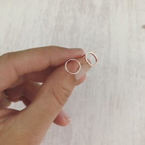 May include: A pair of small, silver hoop earrings. The hoops are simple and circular, with a smooth, polished finish.