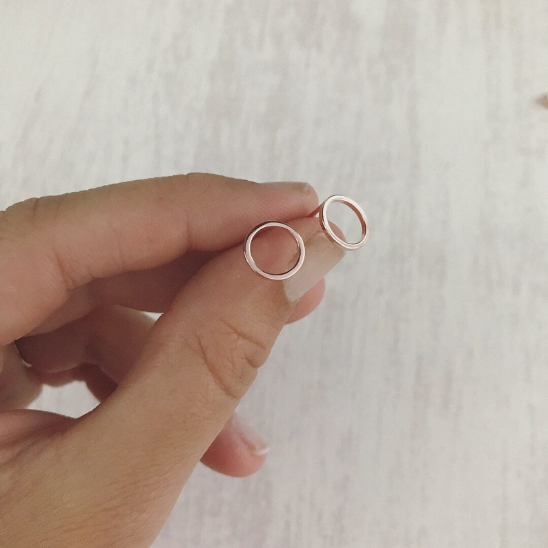 May include: A pair of small, silver hoop earrings. The hoops are simple and circular, with a smooth, polished finish.