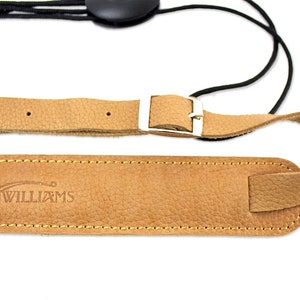 Peut inclure: Une sangle de guitare en cuir marron avec une boucle argent&eacute;e et une sangle &eacute;lastique noire. La sangle est estampill&eacute;e du texte "WALKER & WILLIAMS".