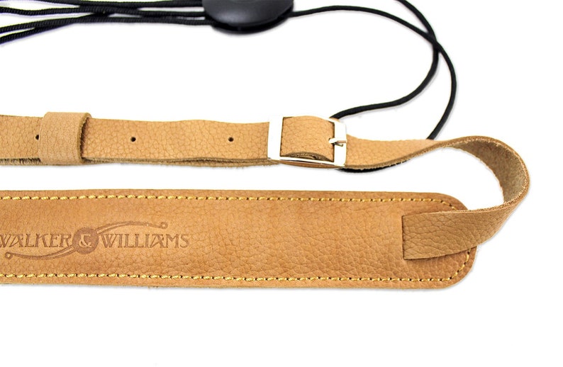 Peut inclure: Une sangle de guitare en cuir marron avec une boucle argent&eacute;e et une sangle &eacute;lastique noire. La sangle est estampill&eacute;e du texte "WALKER & WILLIAMS".