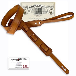 May include: A brown leather guitar strap with a decorative stitching pattern and a buckle. The strap is made by Walker & Williams, a company that has been making fine leather goods since 1894.