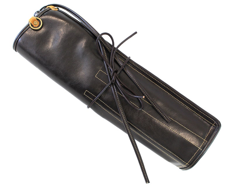 May include: A black leather roll-up case with a yellow stitching detail and a brown leather strap with a metal buckle.