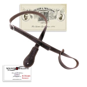 May include: Brown leather guitar strap with a brown leather end strap and a silver metal buckle. The strap is labeled "WALKER & WILLIAMS" and "M-78-BRN MANDOLIN".
