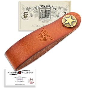 May include: A brown leather guitar strap with a brass star-shaped button and the text "WALKER & WILLIAMS" embossed on it.
