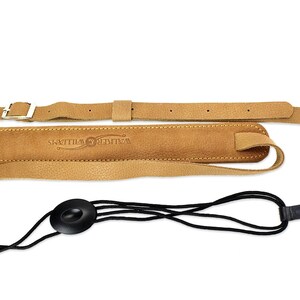 Peut inclure: Sangle de guitare en cuir beige avec une boucle et un verrou de sangle noir. La sangle porte le texte "Walter Williams" en relief.