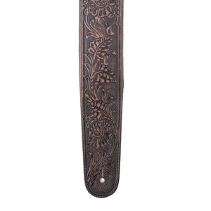 Puede incluir: Una correa de guitarra de cuero marr&oacute;n con un dise&ntilde;o floral en relieve.