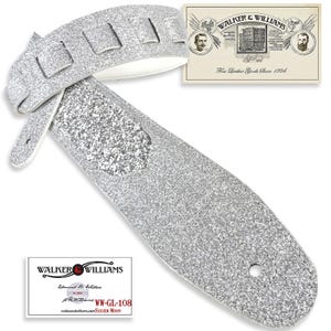 May include: Silver guitar strap with a textured, speckled design. The strap features a padded white underside and multiple adjustment slots. Includes a card with the text "WALKER & WILLIAMS" and "Fine Leather Goods Since 1894".