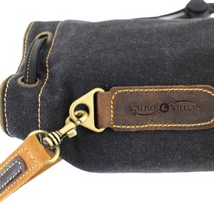 May include: A black canvas drawstring bag with a brown leather strap and a brown leather patch with the text "WALKER & WILLIAMS" embossed on it.