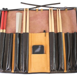 May include: A brown leather drum stick roll-up case with multiple pockets for storing drumsticks, brushes, and other accessories. The case has a flap that closes with a buckle and a strap for carrying.