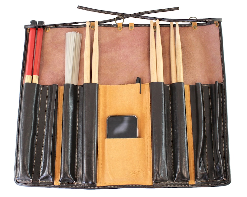 May include: A brown leather drum stick roll-up case with multiple pockets for storing drumsticks, brushes, and other accessories. The case has a flap that closes with a buckle and a strap for carrying.