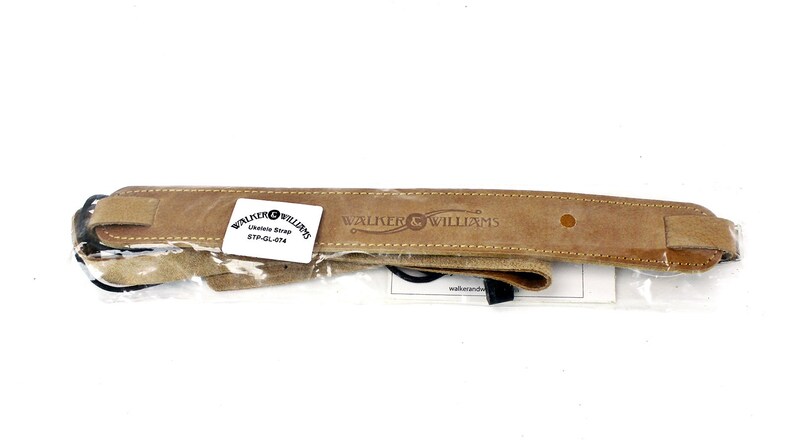 Peut inclure: Une sangle de guitare en cuir marron avec le texte "Walter & Williams" en relief. La sangle est emball&eacute;e dans un sac en plastique transparent.