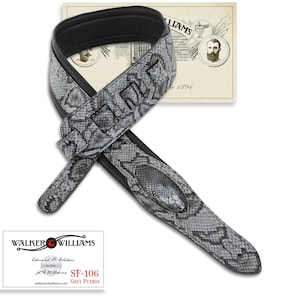 May include: A grey python guitar strap with black accents and a black leather backing. The strap is made by Walker & Williams and has the model number SF-106.